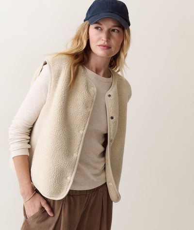 Model wears beige Mila Reversible Sherpa Vest with a matching long-sleeve top and brown pants.