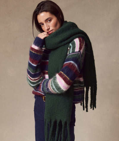 Model wearing a dark green Brushed Scarf with fringe, styled over a striped fuzzy sweater.