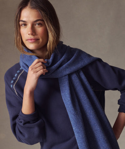 Model wearing the blue Coastal Merino Long Scarf, wrapped around her neck, soft knit texture, close-up view.