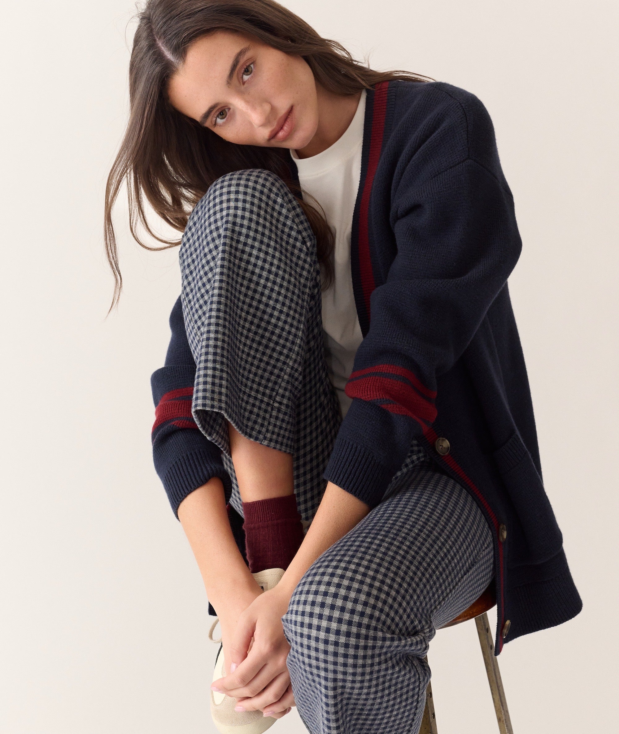 Model wearing Bobbi Flare Pant in a grey and navy gingham check pattern, paired with a navy cardigan.
