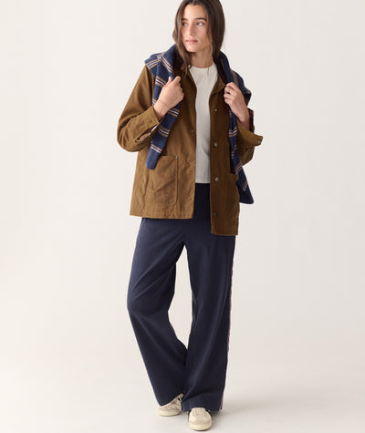 Model wearing brown Riley Barn Jacket, white tee, and navy pants with a striped sweater over shoulders.