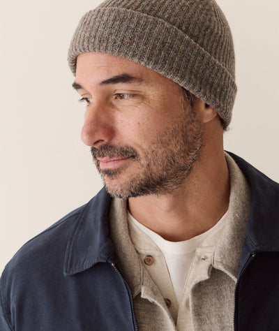 A man wearing a grey speckled Coastal Merino Beanie in a side profile view against a neutral background.