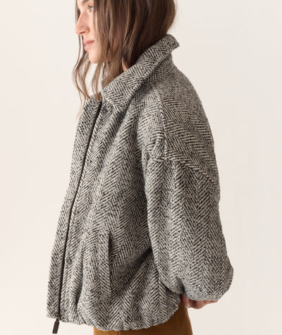 Side view of a woman wearing the grey Chelsea Herringbone Bomber jacket with a zip front and collar.
