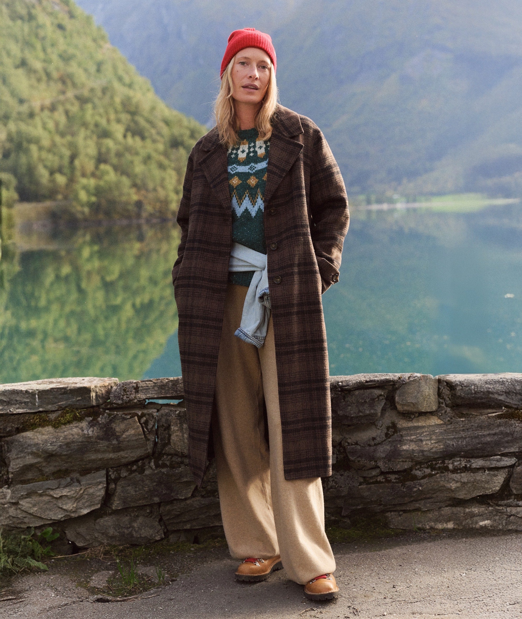 Model wearing brown plaid Colette Wool Topcoat over a patterned sweater, standing by a lake.