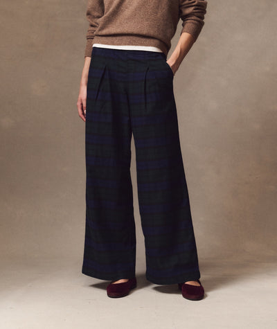 Allison Pleated Moleskin Trouser in navy and green plaid, worn with a brown sweater and burgundy flats.