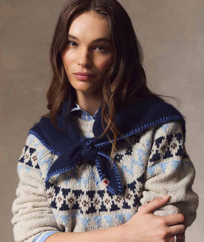 Model wearing navy blue Coastal Merino Triangle Scarf with blanket stitch edge over patterned sweater.
