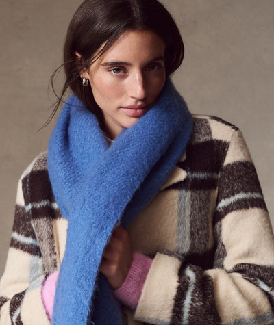 Model wearing a vibrant blue Brushed Scarf over a plaid coat, close-up view.