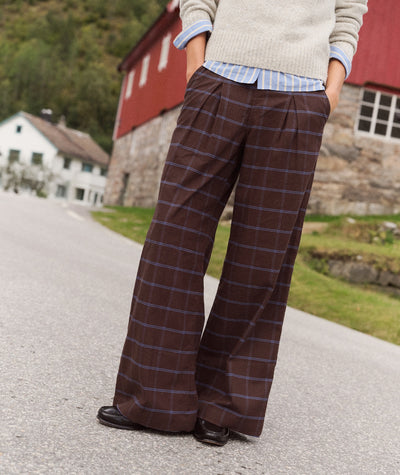 Allison Pleated Moleskin Trouser in brown plaid, worn with a sweater and shirt, showing a full-length view.