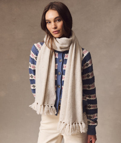 Model wears a cream Coastal Merino Long Scarf with fringe detail over a blue patterned cardigan.
