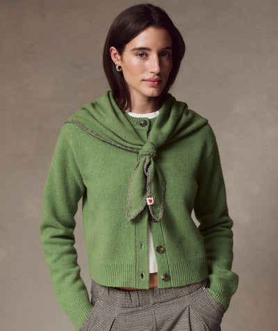 Model wearing the green Coastal Merino Triangle Scarf tied around her neck over a matching cardigan.