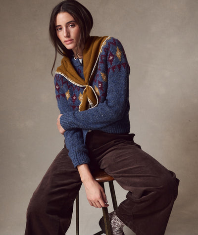 Model wears a mustard Coastal Merino Triangle Scarf over a blue patterned sweater and brown corduroy pants.