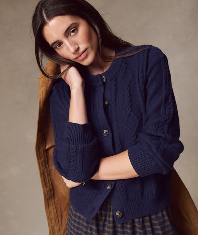 Model wearing navy Everly Cable Knit Cardigan with button front, cable pattern, and ribbed cuffs.