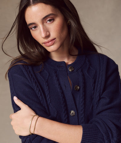 Model wearing the navy blue Everly Cable Knit Cardigan, featuring button-front and cable knit details.