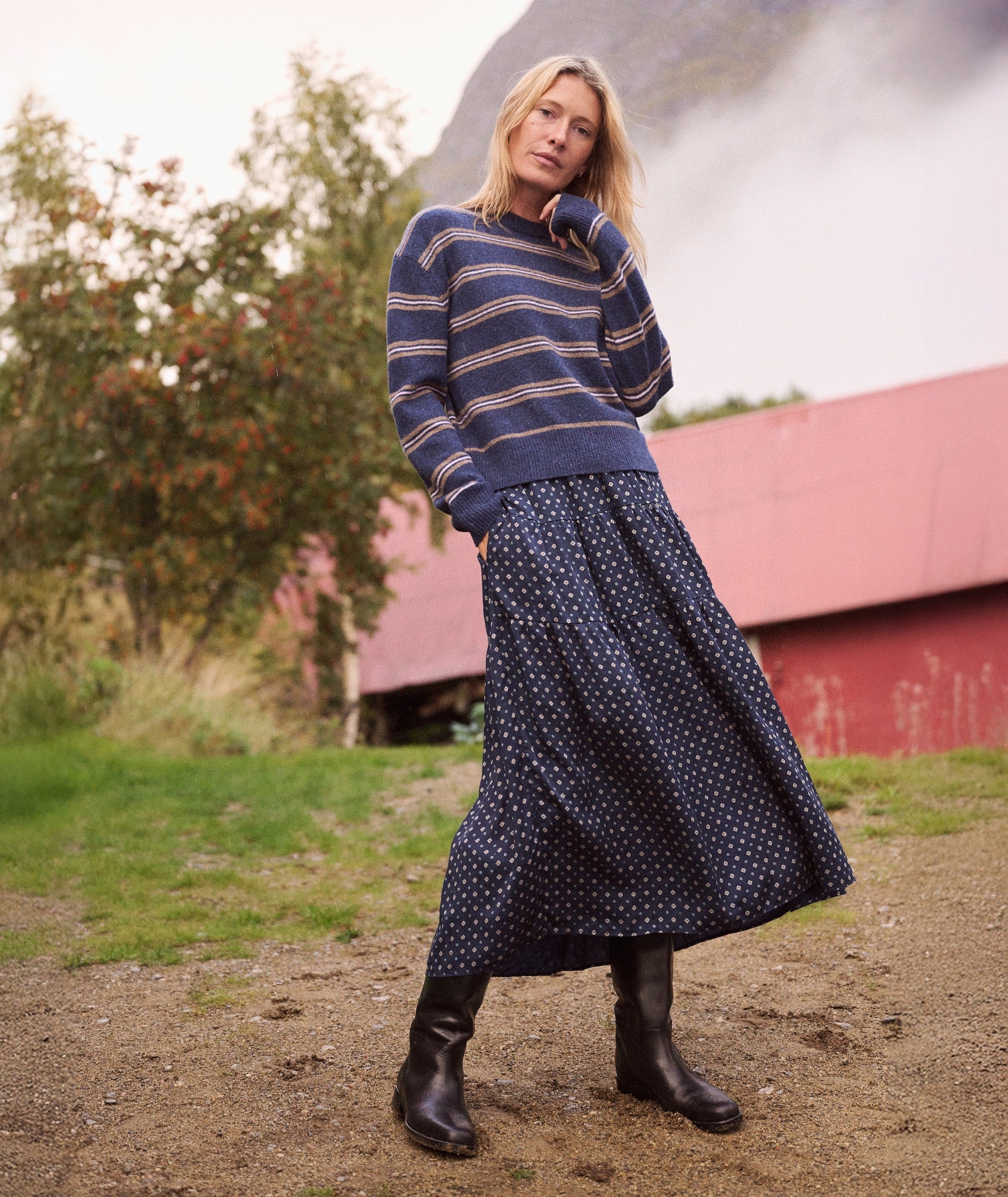 Model wearing the navy floral Gabriela Better-Than-Silk Skirt with a striped sweater and black boots.