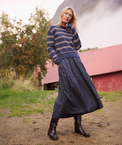Model wearing the navy floral Gabriela Better-Than-Silk Skirt with a striped sweater and black boots.