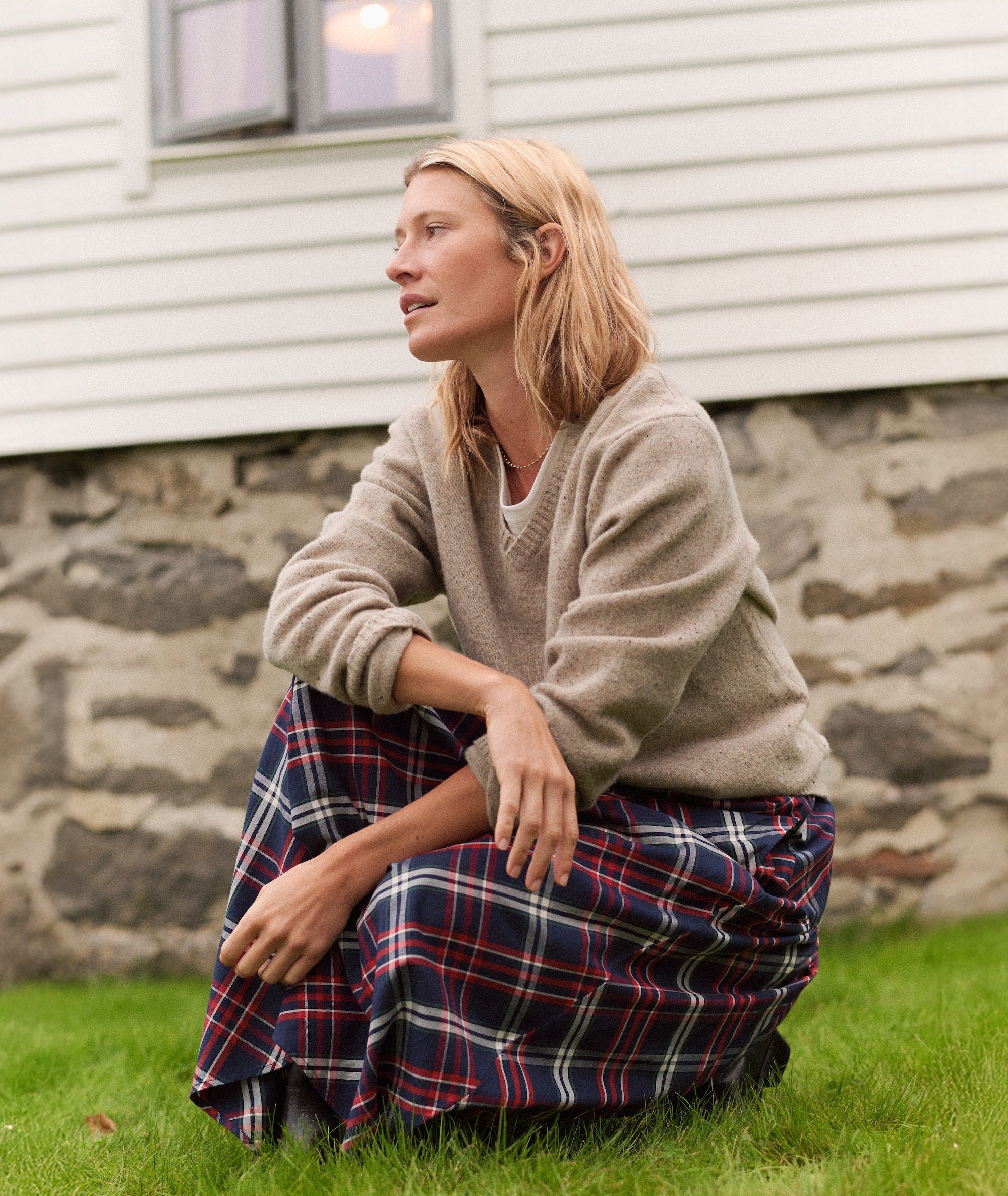 Model wearing the Gia Oxford Midi Skirt in a red, navy, and white plaid pattern, paired with a tan sweater.