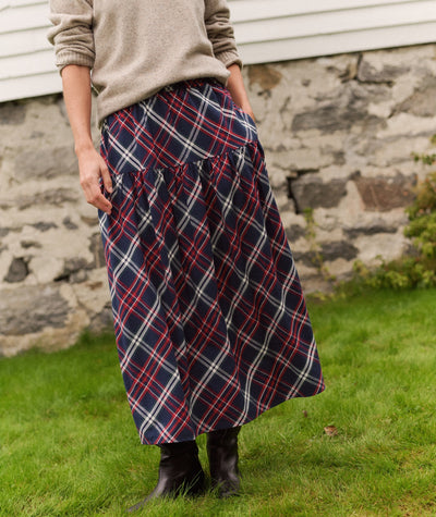 Model wears Gia Oxford Midi Skirt in navy, red, and white plaid with a tiered, gathered hem and side pockets.