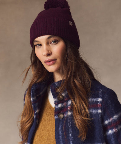 Model wearing the dark burgundy Coastal Merino Pom Beanie with a pom-pom detail.