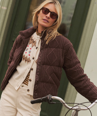 Model wearing the brown Shea Sweater Puffer Jacket with cable-knit details over a patterned cardigan.