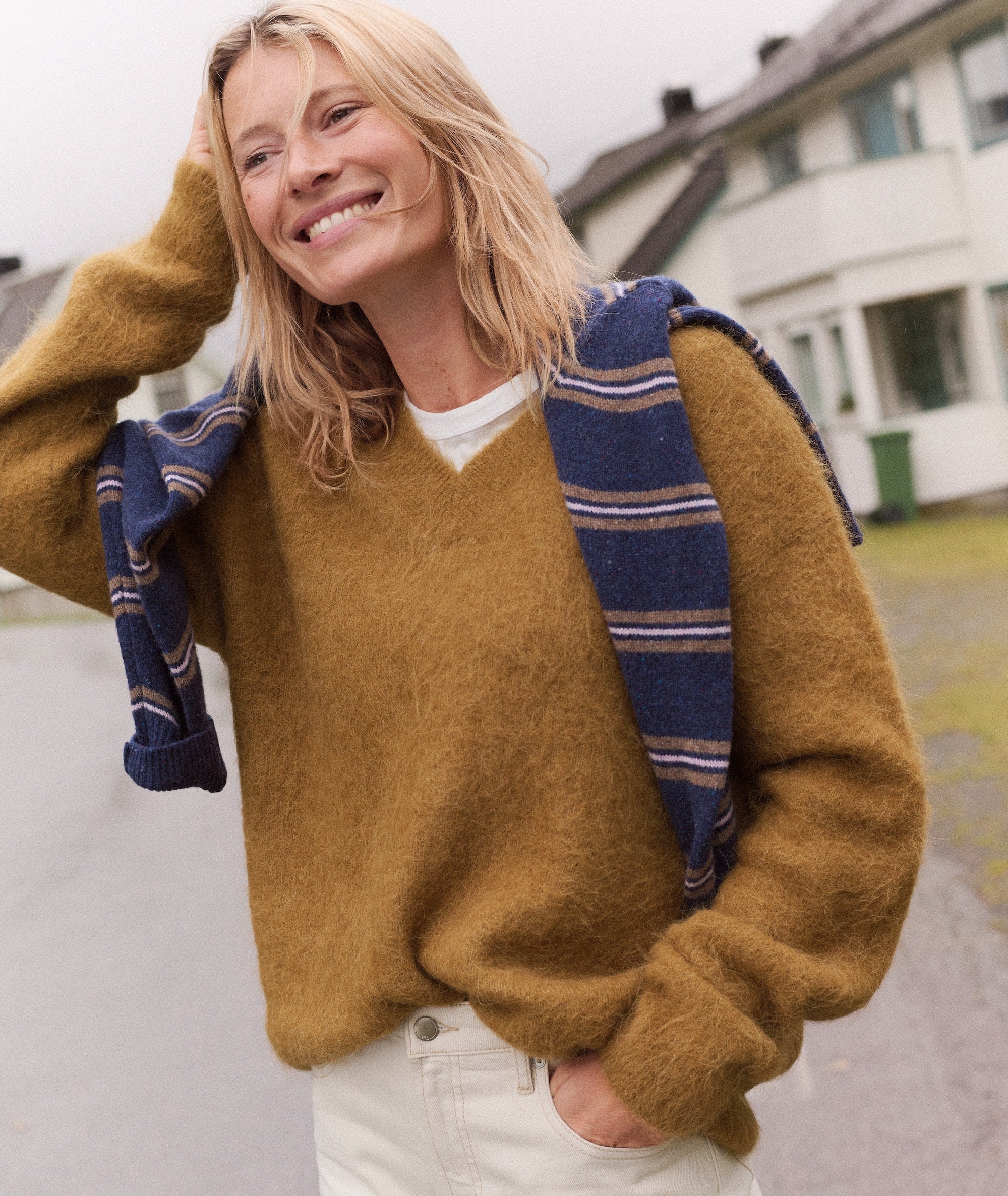 Model wearing a mustard yellow Suri Alpaca V-Neck Sweater with a striped scarf draped over shoulders.