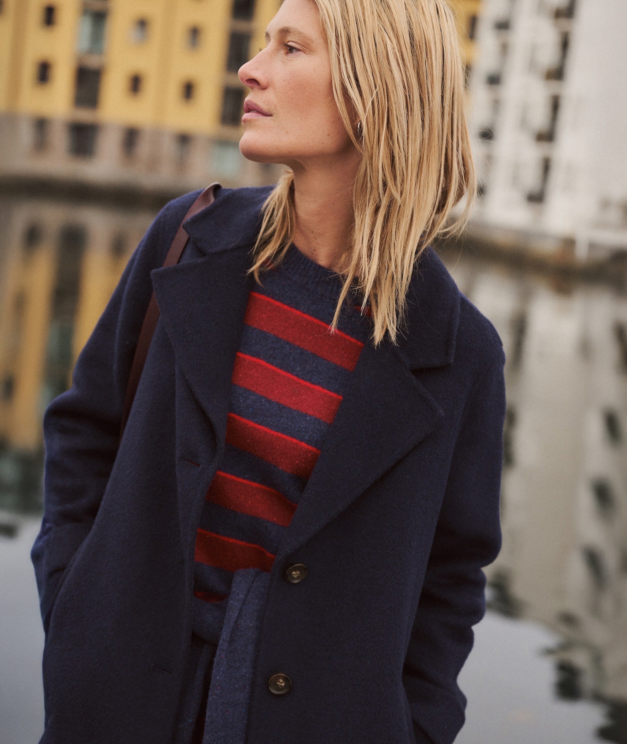 Model wearing navy Colette Wool Topcoat over a red and navy striped sweater, side view.