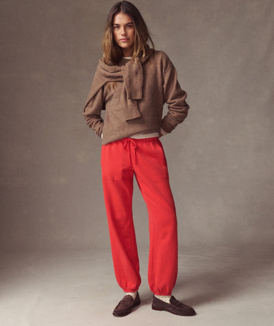 Model wearing bright red Cloud 9 Fleece Sweatpant with brown sweater and loafers, full-body view.